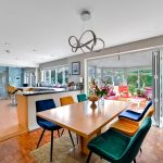 Modern dining area with colourful chairs and garden view.