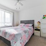 Cosy bedroom with floral quilt and natural light.