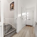 White hallway with staircase and front door.