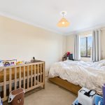 Bedroom with crib and double bed with window view.