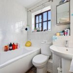 Bright bathroom with bathtub, toilet, sink and toiletries.