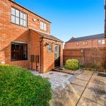 Brick house with garden and wooden fence.
