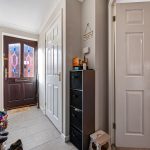 Hallway with tiled floor and wooden front door.