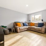 Modern lounge with grey walls and beige sofa.