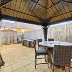 Patio with gazebo, dining set, and shed in garden.