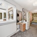 Cosy bedroom with floral wallpaper and large mirror.
