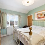Cosy bedroom with framed art above metal bed.