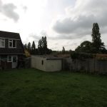 Suburban garden with lawn and shed under cloudy sky.
