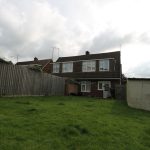 Back garden with grass, fence, house view.