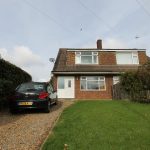 Brick house, car on driveway, green lawn