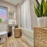 Modern bathroom with plants and wicker baskets.