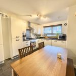 Modern kitchen with wooden table and white cabinets.