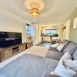 Modern living room with grey sofa and large TV.