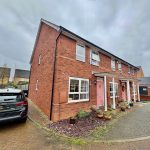 Red brick house with pink doors and parked car.