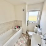 Modern bathroom with bathtub, window, and sink.