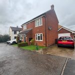 Red brick house with parked cars in driveway.