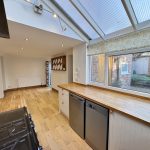 Spacious kitchen with wooden floors and large windows.