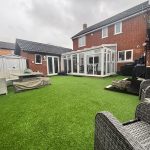 Back garden with patio furniture and conservatory.