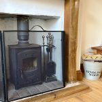 Wood stove with kindling bucket and tools nearby.