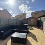 Sunny patio with garden shed and seating area.