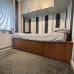 Single bed in modern bedroom with striped walls.