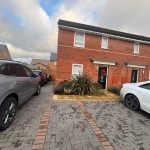 Driveway with cars by red-brick house.